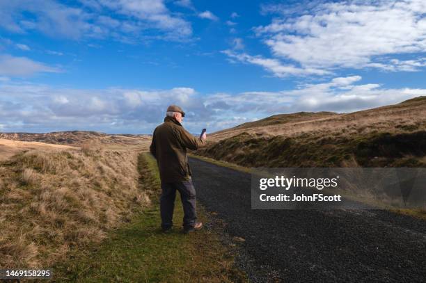 senior man in a rural scene using at his mobile phone - waxed jacket stock pictures, royalty-free photos & images