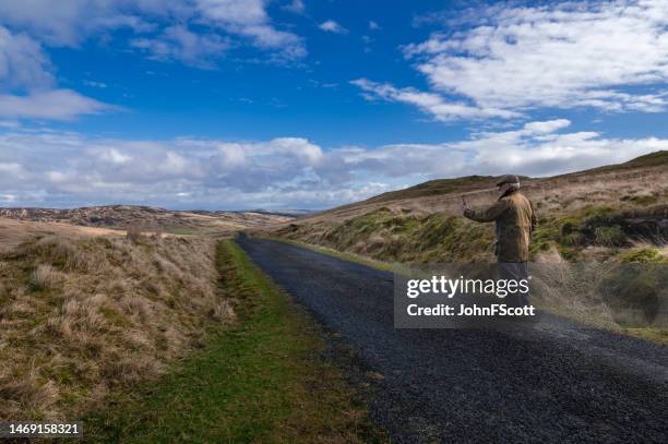 senior man in a rural scene using at his phone - waxed jacket stock pictures, royalty-free photos & images