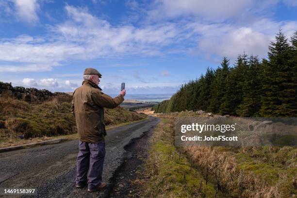 mature man in a rural scene using at his phone - waxed jacket stock pictures, royalty-free photos & images