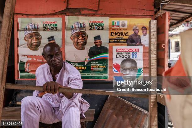 Man sits in of front campaign posters at Lagos Island on February 23, 2023 in Lagos, Nigeria. Nigerians are preparing to elect the next president of...