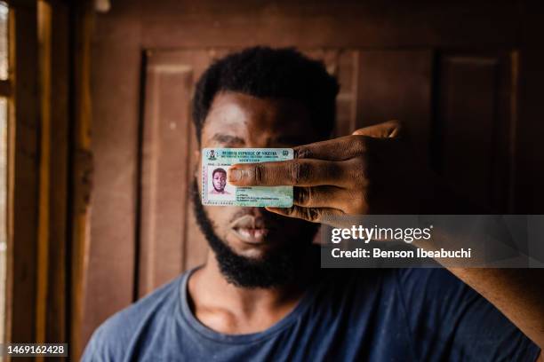 Youth showing his Permanent Voters Card while covering his face at Akoka on February 23, 2023 in Lagos, Nigeria. Nigerians are preparing to elect the...