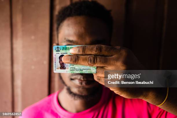 Youth showing his Permanent Voters Card while covering his face at Akoka on February 23, 2023 in Lagos, Nigeria. Nigerians are preparing to elect the...