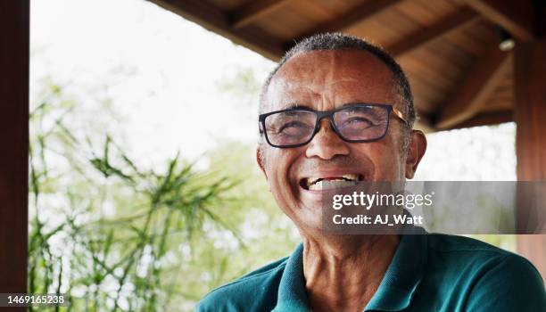 mature man laughing while sitting outdoors on his patio at home - one mature man only stock pictures, royalty-free photos & images