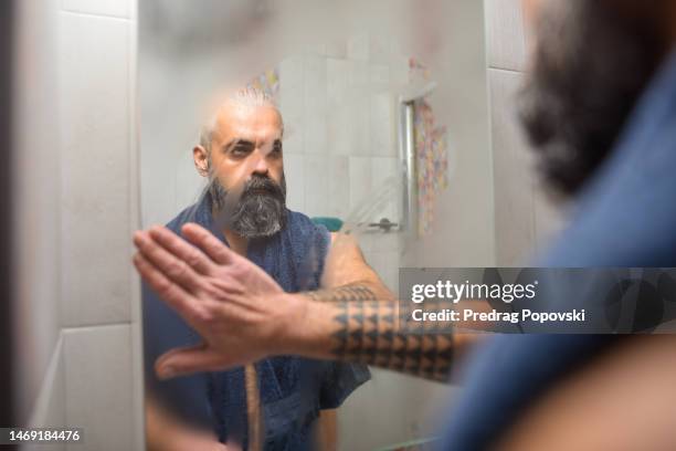 good looking man cleaning mirror steam after shower - mirror steam stockfoto's en -beelden