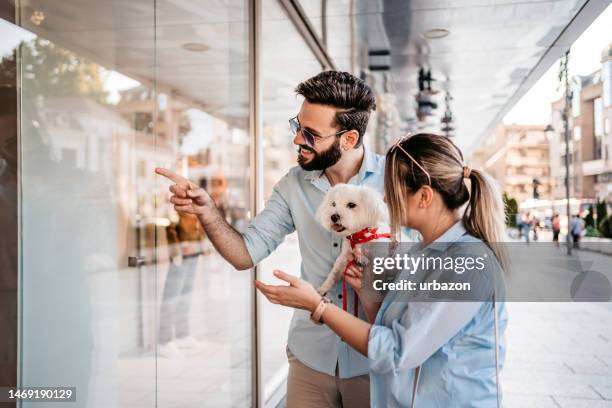 young couple window shopping with their dog - couple shopping stock pictures, royalty-free photos & images