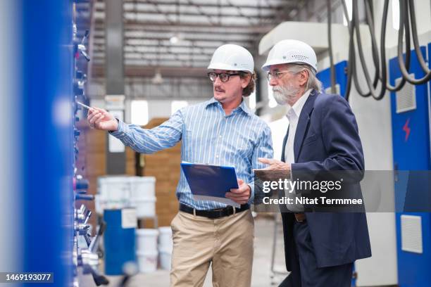 calculate the return on investment (roi) of a manufacturing execution system for entrepreneurs and growing a successful business. business partner having a discussion in the printing press machine of carton box for an investment plan. - execution stock pictures, royalty-free photos & images