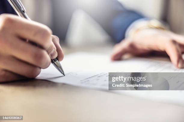 a businessman's hand signs an invoice, loan, car leasing or other document. - contratto foto e immagini stock