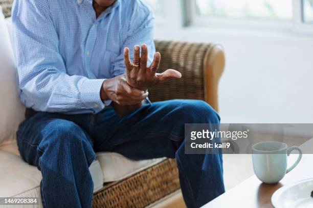 älterer afroamerikanischer mann mit handgelenkschmerzen - sehnenscheidenentzündung stock-fotos und bilder
