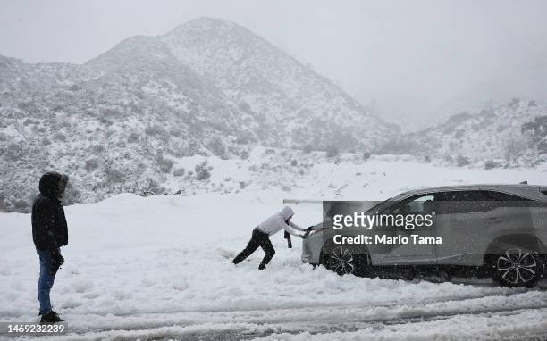Person helps push out a car that became stuck in the snow on a roadway in Los Angeles County, in the San Gabriel Mountains in Angeles National...