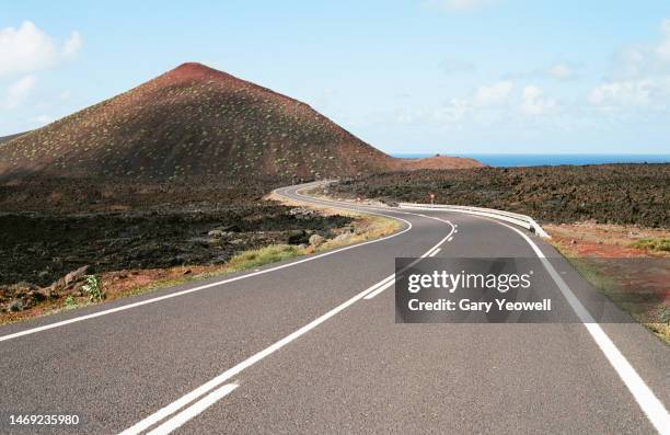 winding road leading into the distance in volcanic landscape - strada tortuosa foto e immagini stock