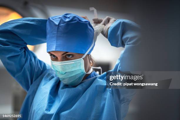 the surgeon is wearing a mask to prevent infection before surgery. - chirurgien photos et images de collection
