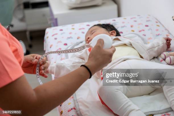 doctor with a tape measure about to measure a baby, in her doctor's office - baby m stock pictures, royalty-free photos & images