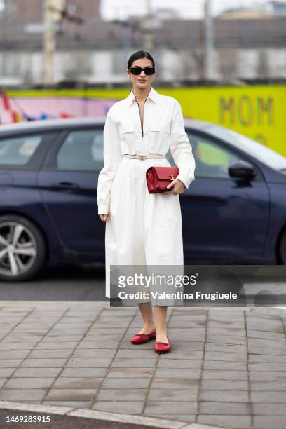 Guest is seen wearing a zipper belted dress with pockets and To's bag and red ballerinas outside the Tod's show during the Milan Fashion Week...