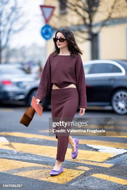 Alexandra Pereira is seen wearing brown sunglasses, gold earrings, a purple plum coord-set made of a long-sleeves asymmetrical shirt and a low-waist...