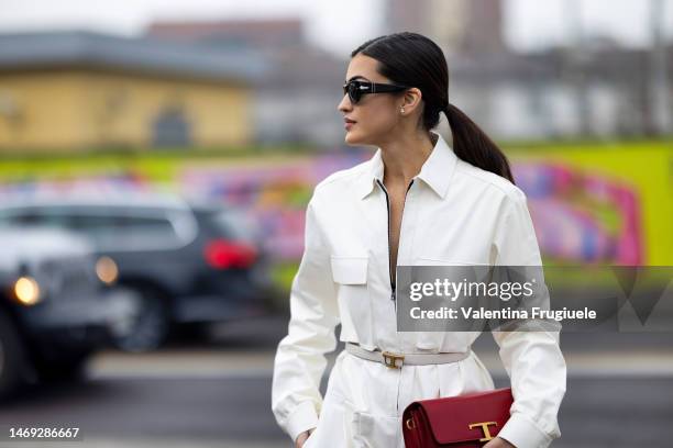 Guest is seen wearing a zipper belted dress with pockets and To's bag and red ballerinas outside the Tod's show during the Milan Fashion Week...