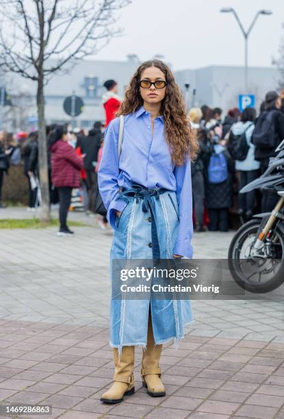 Sarah Lysander wears blue button shirt, long denim skirt, sunglasses, beige boots outside Tods during the Milan Fashion Week Womenswear Fall/Winter...