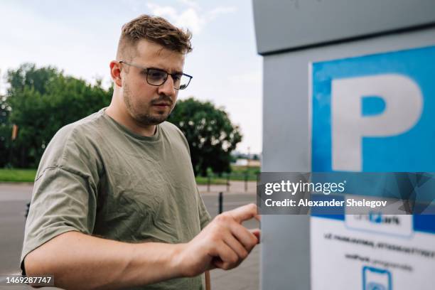 person is using parking terminal for paying the station. male portrait of man wear t-shirt and eyeglasses outdoors. lifestyle photography concept. - automatic gearshift stock pictures, royalty-free photos & images