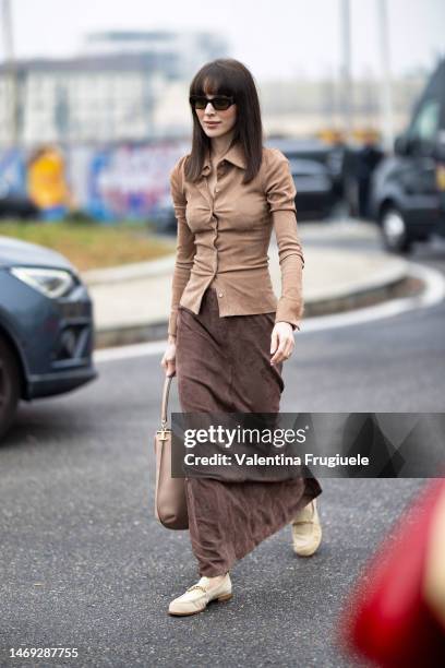 Mary Leest is seen wearing black sunglasses, gold rings, a beige suede shirt, a brown maxi long suede skirt, a beige leather Tod's bag with gold...