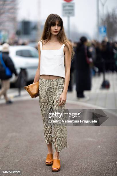 Mara Lafontan is seen wearing gold rings, a white high-low leather tank-top, a snake print cut-out long low-waist skirt, a Tod's leather handbag with...