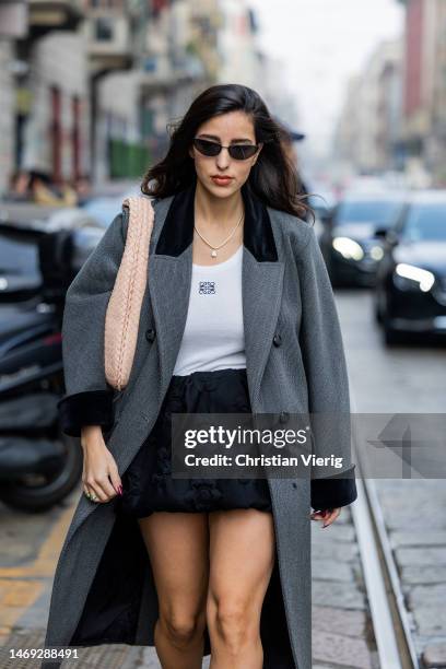 Bettina Looney wears grey oversized coat, white Loewe top, salmon colored bag, black skirt outside Sportmax during the Milan Fashion Week Womenswear...