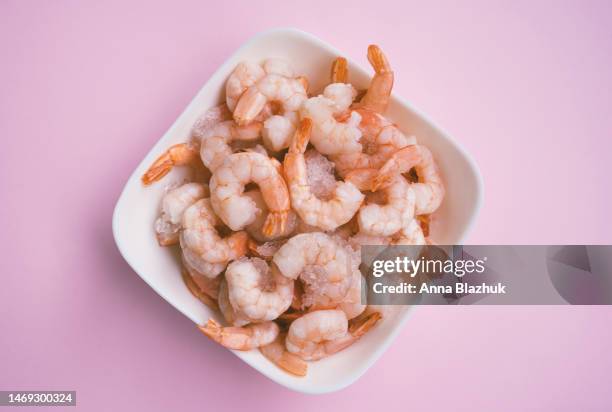fresh raw shrimps in white plate on pink background - prawn stock-fotos und bilder