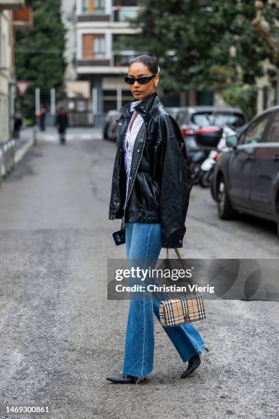 Jamilla Strand wears flared ripped denim jeans, black leather jacket, white button shirt outside Sunnei during the Milan Fashion Week Womenswear...