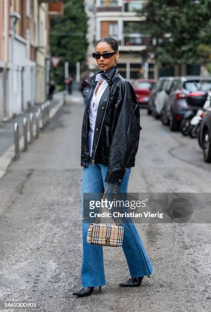 Jamilla Strand wears flared ripped denim jeans, black leather jacket, white button shirt outside Sunnei during the Milan Fashion Week Womenswear...