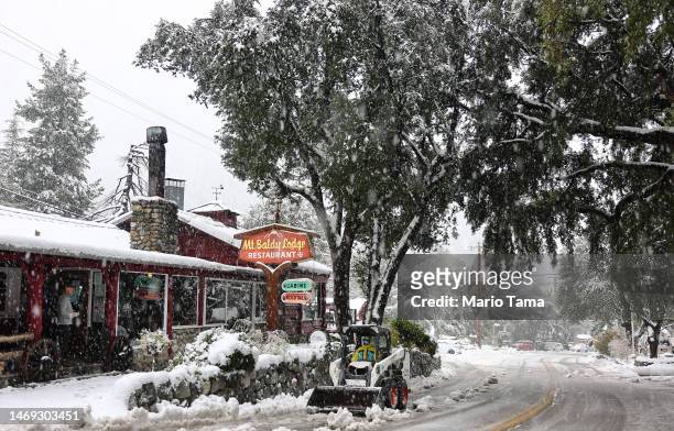 Vehicle clears snow in front of a restaurant as snow falls in the San Gabriel Mountains in San Bernardino County near Los Angeles County, on February...