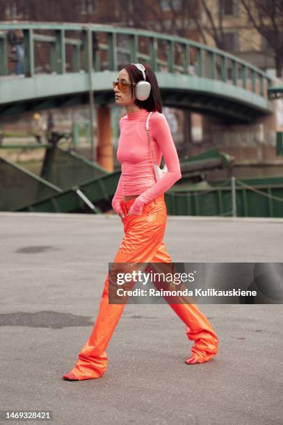 Alexandra Guerain is seen wearing a pink turtle neck top, orange pants, silver headphones, and a white bag outside Sportmax during the Milan Fashion...