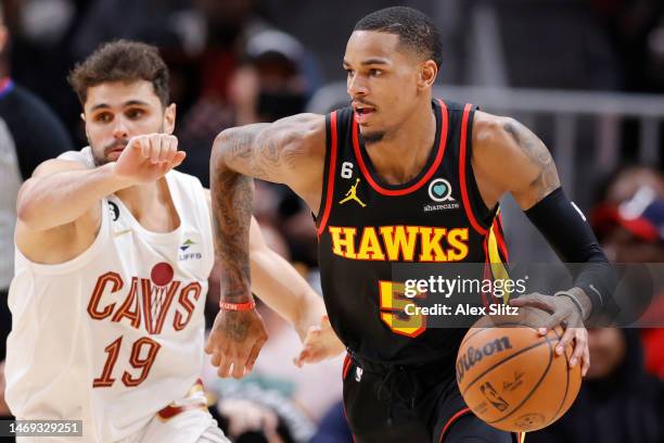 Dejounte Murray of the Atlanta Hawks dribbles the ball around Raul Neto of the Cleveland Cavaliers during the first half at State Farm Arena on...