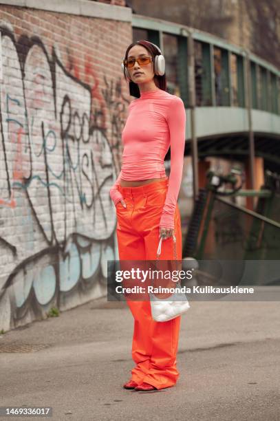 Alexandra Guerain is seen wearing a pink turtle neck top, orange pants, silver headphones, and a white bag outside Sportmax during the Milan Fashion...