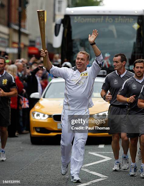 Torchbearer and British cyclist Sir Chris Hoy carries the Olympic Flame on the Torch Relay leg between Lytham St Anne's and Manchester on June 23,...