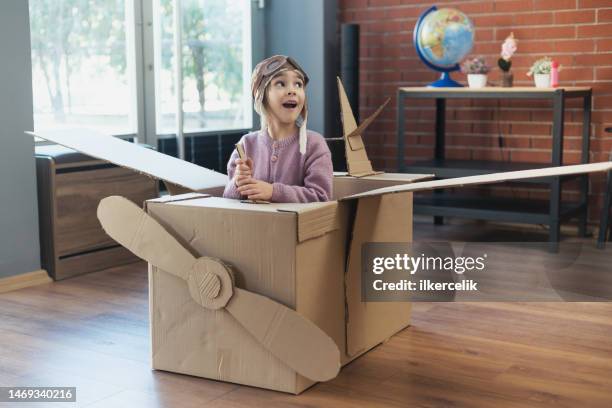 niña divirtiéndose jugando con el avión de cartón en casa - caja cartón fotografías e imágenes de stock