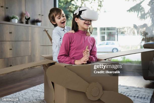 children having fun playing with virtual reality simulator in a plane from cardboard box - cardboard vr stock pictures, royalty-free photos & images