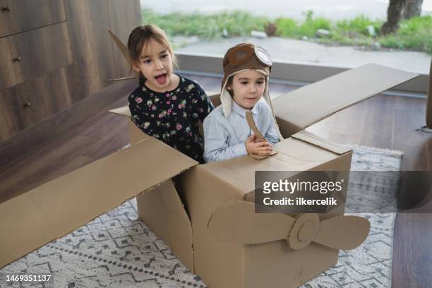 children having fun playing with the plane from cardboard at home - boys toys stock pictures, royalty-free photos & images