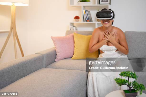 excited young woman wearing virtual reality glasses to watch videos, sitting with her hands on her chest - woman flat chest 個照片及圖片檔