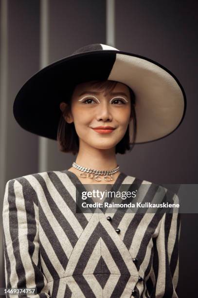 Elva Ni is seen wearing a geometrical striped black and white dress, Gucci letter neckless, wide-brimmed black and white hat, Gucci Jackie 1961 bag,...