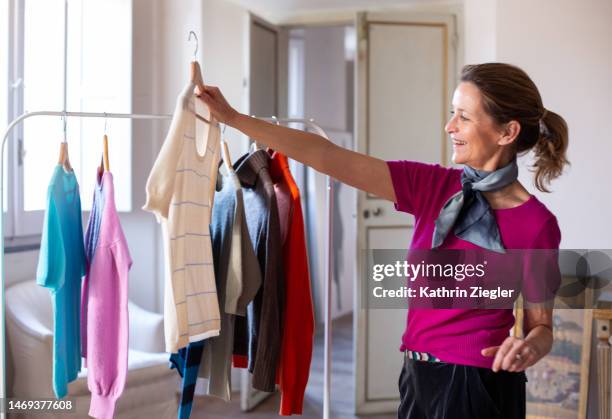 woman taking cashmere sweater off a rack to look at it - clothes on clothes off photos 個照片及圖片檔