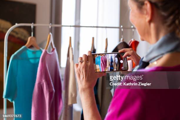 woman taking pictures of cashmere sweaters on a clothes rail - photographing clothes stock pictures, royalty-free photos & images