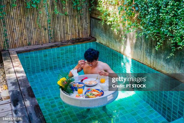 man with morning floating food at private floating pool - overhead pool table stock-fotos und bilder