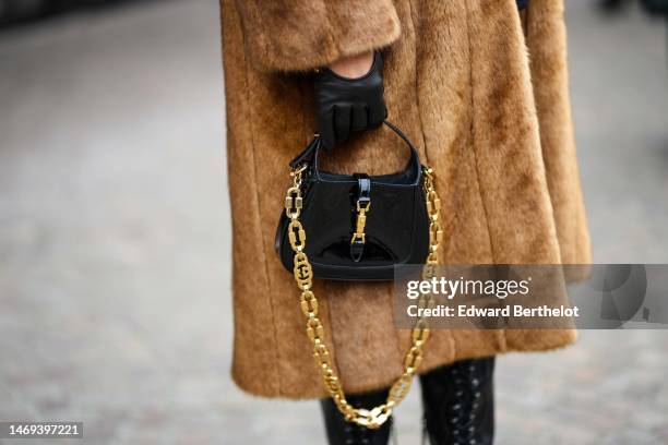 Caroline Daur wears a brown fur with blue collar / shoulder-pads long coat, black shiny leather gloves, a black shiny leather handbag from Gucci,...