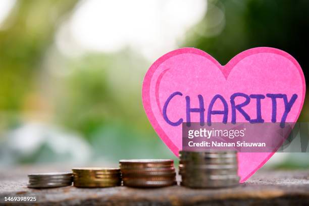 paper heart with text charity and coins on wooden - money donation stock-fotos und bilder