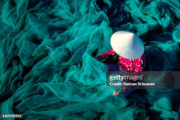 woman knitting net in vietnam - sombrero asiático fotografías e imágenes de stock