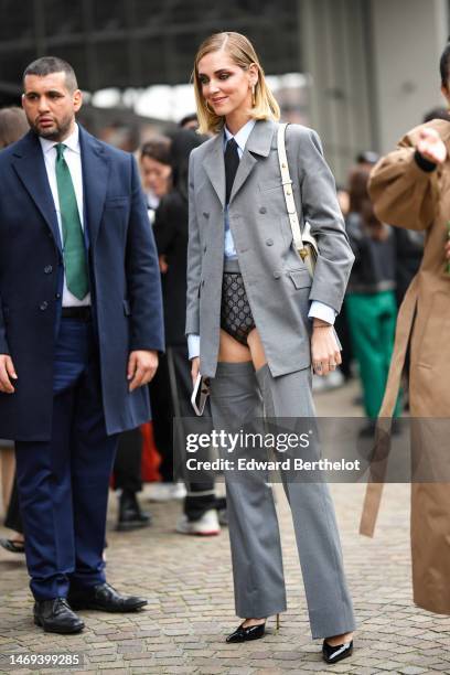 Chiara Ferragni wears gold earrings, a white shirt, a black tie, a pale blue shirt, black lace print pattern transparent micro shorts, a gray blazer...