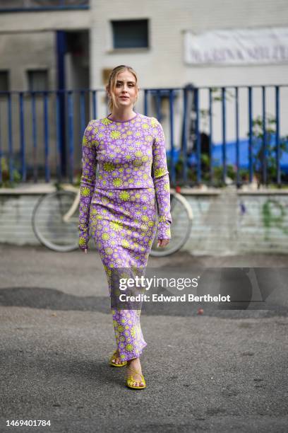 Valentina Ferragni wears a purple with yellow flower print pattern long sleeves long tube dress, yellow shiny leather strappy heels mules shoes ,...