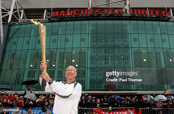 Ex Manchester United and England football player Sir Bobby Charlton carries the Olympic Flame on the Torch Relay leg between Salford and Leeds on...