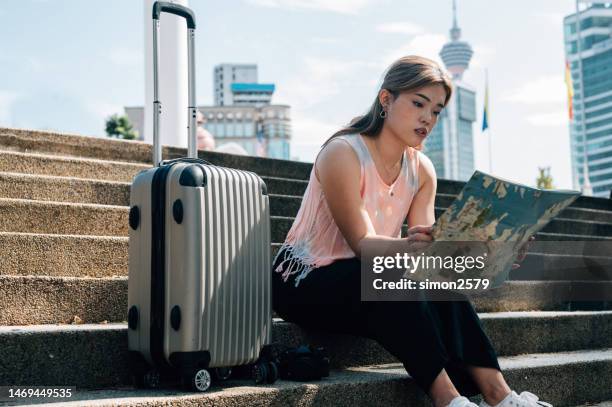 tourist with city plan sitting on a staircase - malaysia kuala lumpur merdeka square stock pictures, royalty-free photos & images