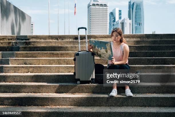 beautiful asian woman on vacation taking a break and exploring the city map - malaysia kuala lumpur merdeka square stock pictures, royalty-free photos & images