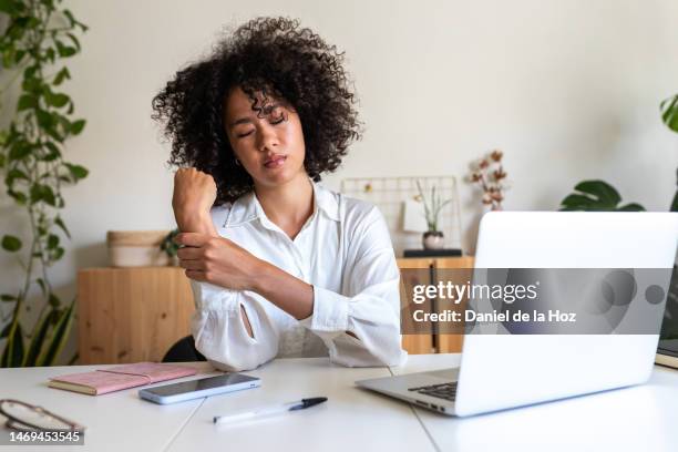 african american woman suffering from wrist pain from working with laptop at home office. - karpaltunnelsyndrom bildbanksfoton och bilder