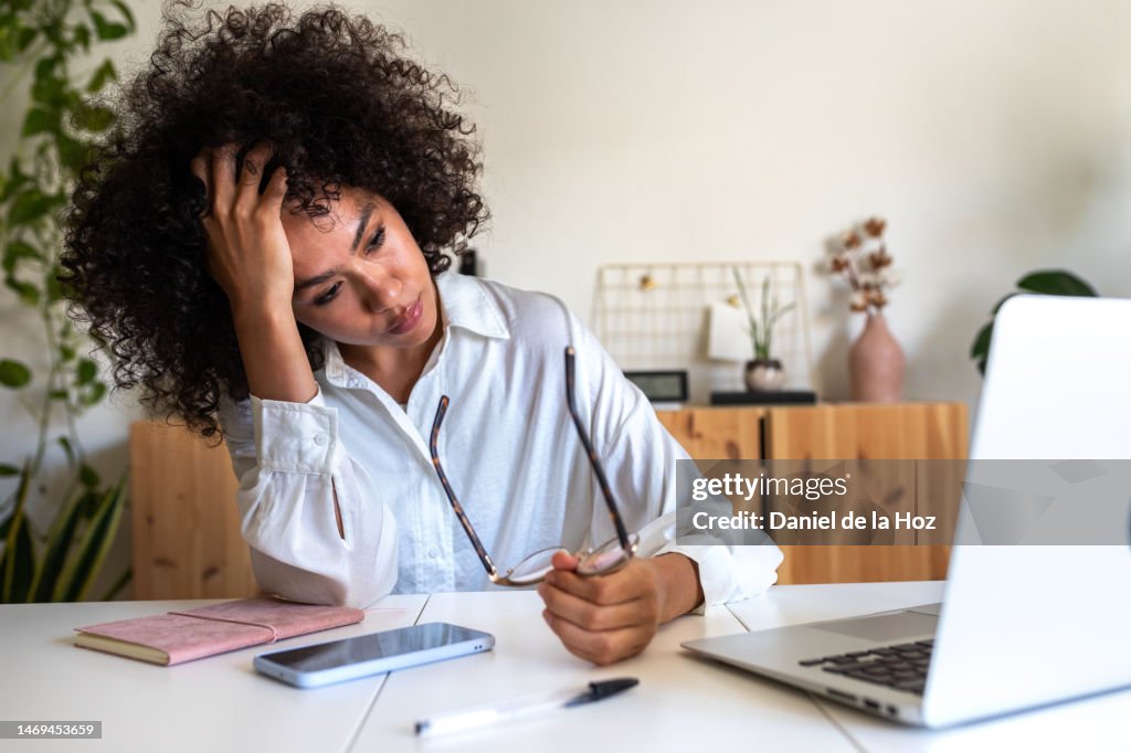 Young African American woman feeling exhausted and depressed sitting in front of laptop. Work burnout syndrome.